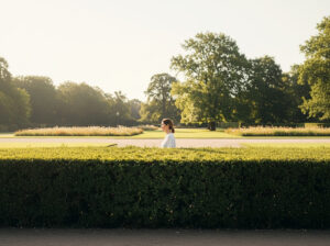 Eine Frau geht hinter einer Hecke entlang
